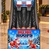 Ho Ho Hoops Christmas-dressed two-player arcade basketball game with Santa and reindeer artwork, set up in a hotel lobby for a corporate Christmas party (concept artwork)